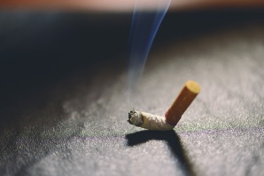 lit-cigarette-butt-with-smoke-on-the-ground-PLURDK7